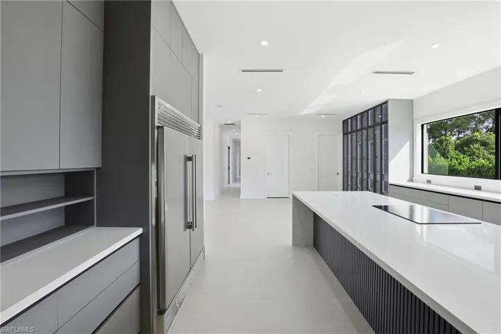 Kitchen featuring modern cabinets, gray cabinetry, built in refrigerator, black electric stovetop, and recessed lighting