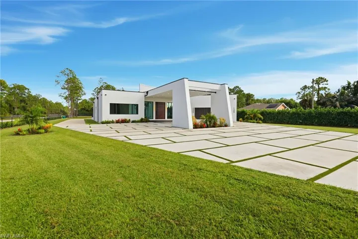 Back of house featuring a lawn and stucco siding