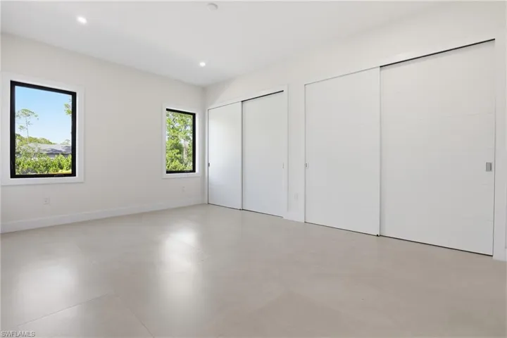 Unfurnished bedroom with two closets, recessed lighting, and finished concrete floors