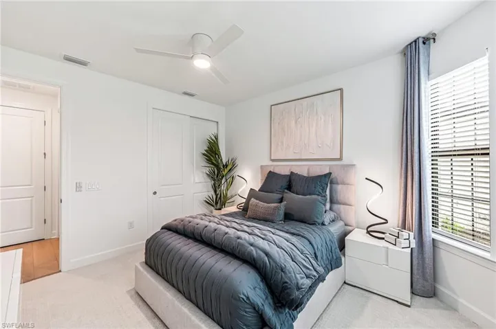 Bedroom featuring light colored carpet, ceiling fan, and a closet