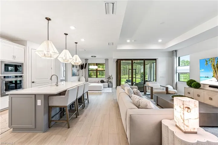 Living room with light wood-type flooring, plenty of natural light, a notable chandelier, and sink