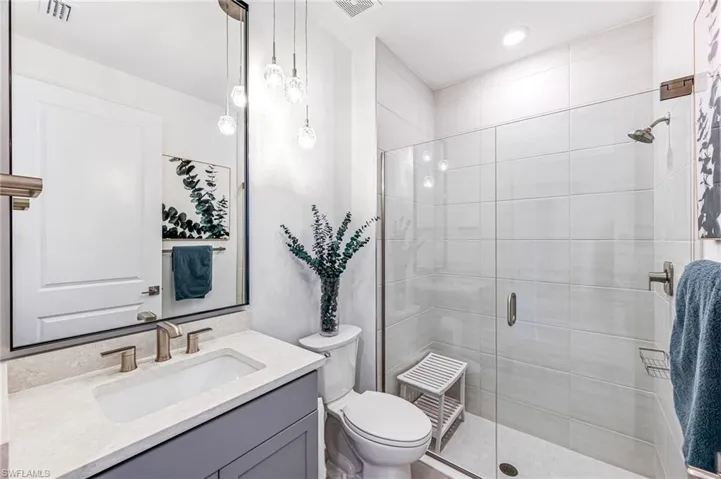 Bathroom with a shower with shower door, toilet, and vanity