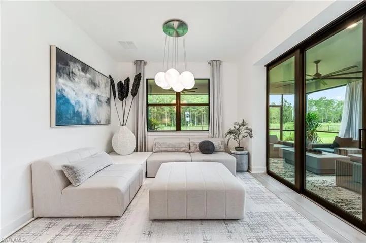 Living room with a wealth of natural light, ceiling fan with notable chandelier, and light hardwood / wood-style floors