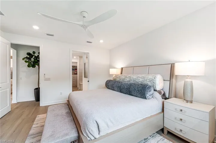 Bedroom with ceiling fan, ensuite bathroom, and light hardwood / wood-style flooring