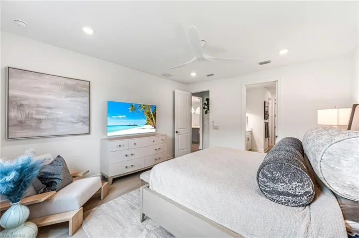 Bedroom with ensuite bath, light wood-type flooring, and ceiling fan