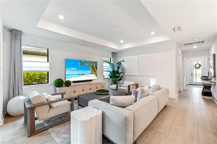 Living room featuring a wealth of natural light, a raised ceiling, and light hardwood / wood-style floors