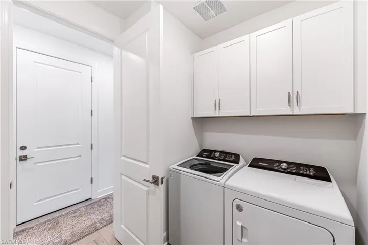 Washroom with cabinets and washer and clothes dryer