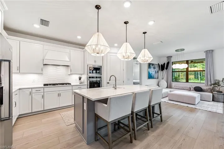 Kitchen with appliances with stainless steel finishes, premium range hood, white cabinetry, and sink