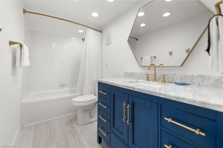Primary Bathroom featuring vanity, recessed lighting, shower / bath combination with curtain, and light wood-style flooring