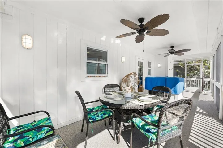 Screened lanai with a ceiling fan and an outdoor living / dining area