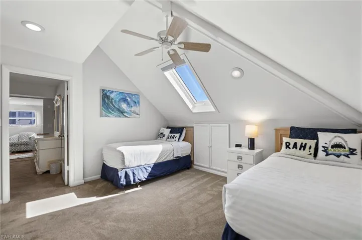 Loft featuring a skylight, carpet flooring, lofted ceiling, and ceiling fan