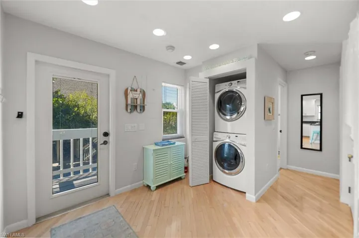 Laundry area featuring stacked washer and dryer, light wood finished floors, and recessed lighting