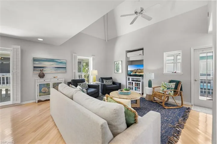 Living room with light wood-style flooring, ceiling fan, and lofted ceiling