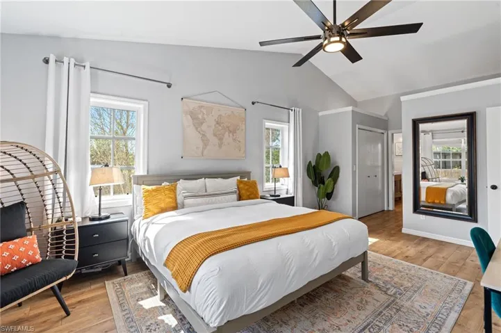 Bedroom with a ceiling fan, light wood-style flooring, and vaulted ceiling