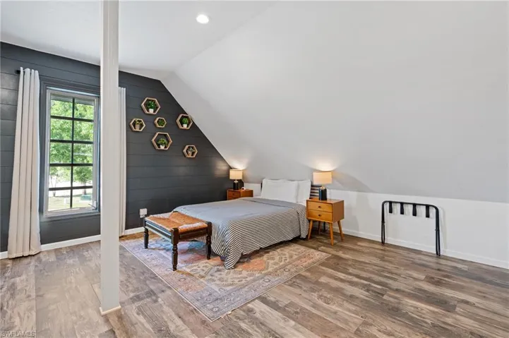 Bedroom with lofted ceiling, wood finished floors, and baseboards