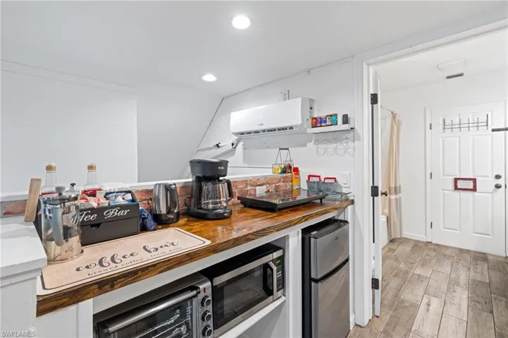 Kitchen featuring recessed lighting, light wood-style flooring, appliances with stainless steel finishes, a wall mounted air conditioner, and wooden counters