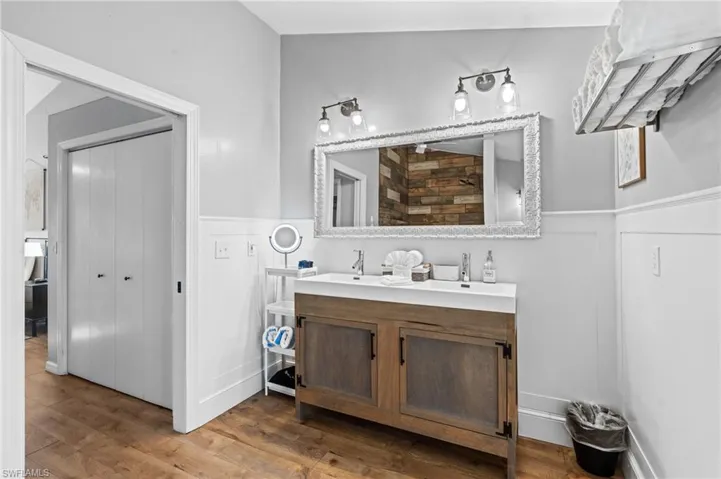 Bathroom featuring double vanity, wood finished floors, and a wainscoted wall