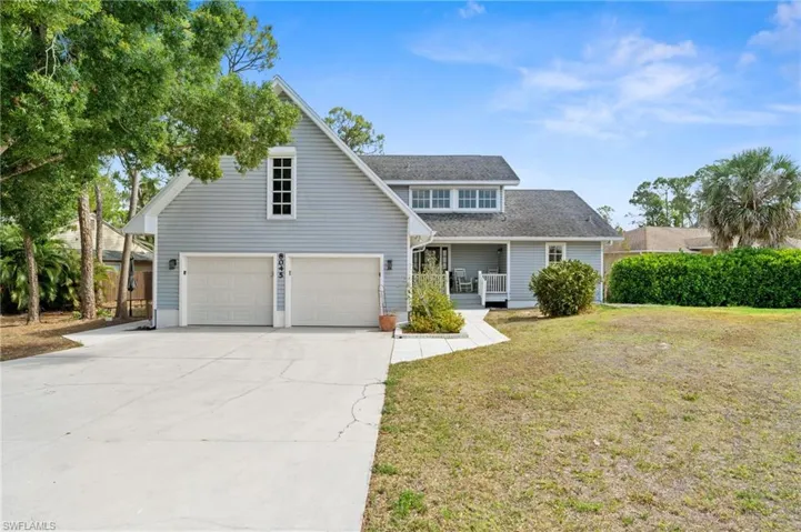 Traditional home with covered porch, roof with shingles, a front yard, concrete driveway, and an attached garage