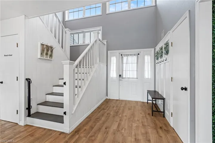Entrance foyer with a high ceiling, stairs, and wood finished floors