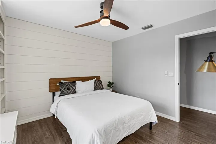 Bedroom with wood finished floors, ceiling fan, visible vents, and baseboards