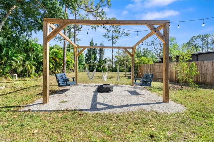 View of jungle gym with fence, a lawn, and a patio