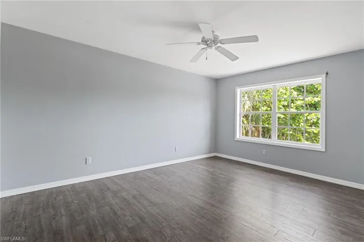 Spare room featuring dark wood finished floors, baseboards, and a ceiling fan