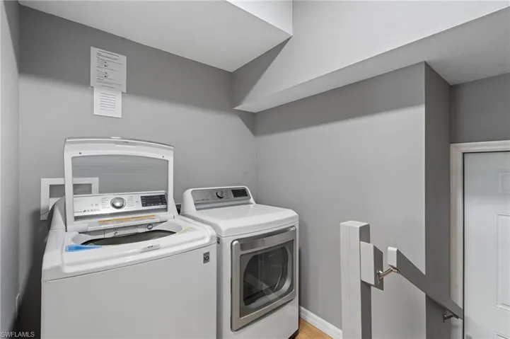 Clothes washing area featuring separate washer and dryer, laundry area, and light wood-style flooring