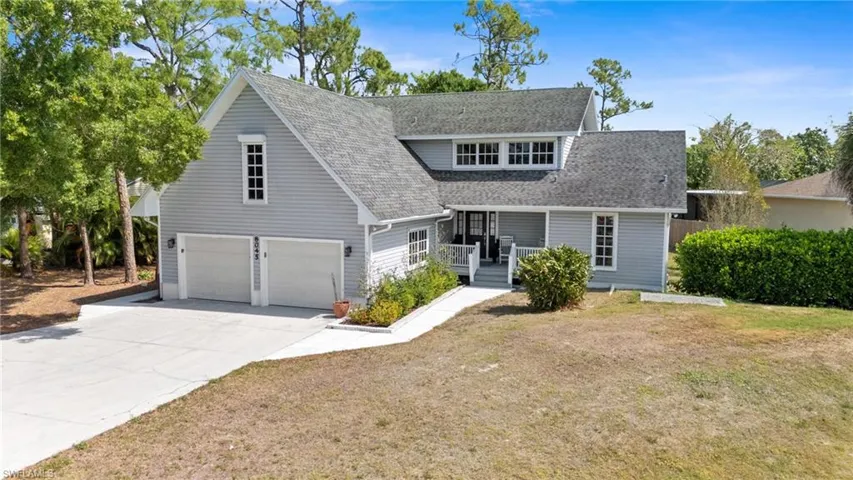 View of front facade featuring covered porch, a front yard, concrete driveway, and roof with shingles