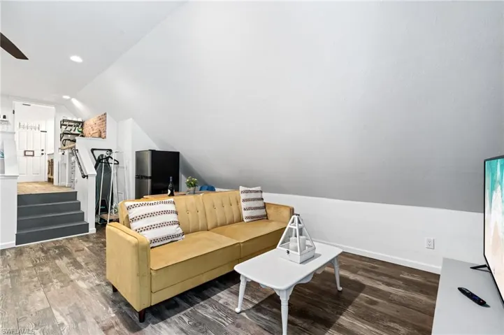 Living room featuring lofted ceiling, wood finished floors, a ceiling fan, and baseboards