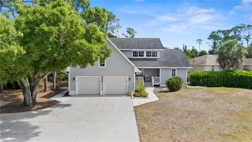 View of front facade featuring a front yard, a garage, covered porch, driveway, and roof with shingles