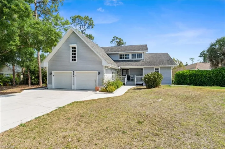 Traditional home featuring a front yard, a shingled roof, covered porch, driveway, and an attached garage
