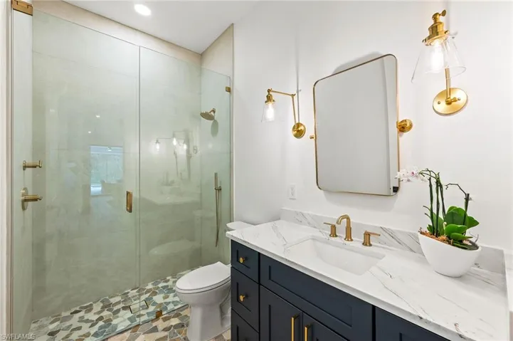 Bathroom featuring a shower with door, vanity, and toilet