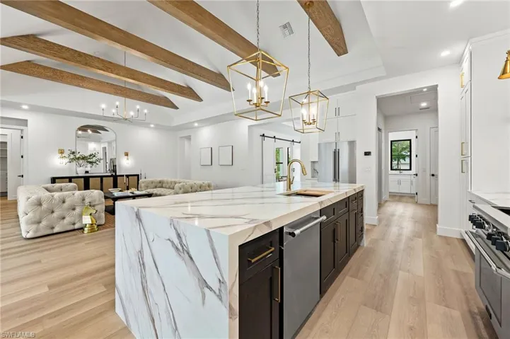 Kitchen featuring high end appliances, a large island with sink, a barn door, and decorative light fixtures