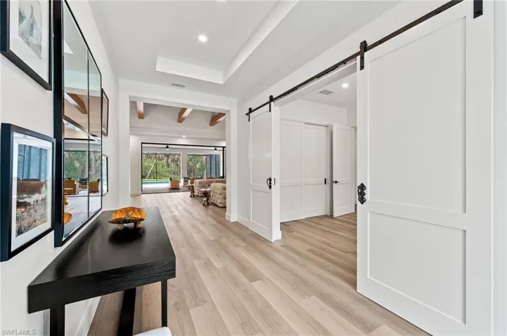 Hallway featuring a barn door, light hardwood / wood-style floors, and a raised ceiling