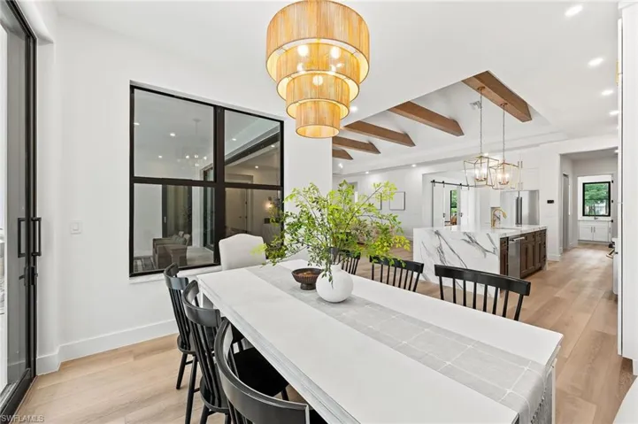 Dining room with light hardwood / wood-style floors, a notable chandelier and beam ceiling