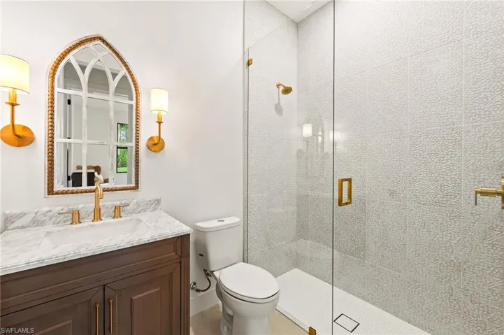 Bathroom featuring vanity, toilet, and a shower with door