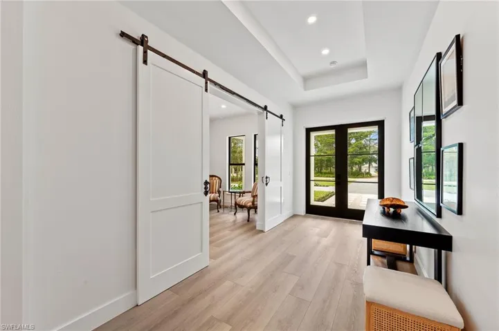 Entryway featuring french doors, light hardwood / wood-style floors, a barn door, and a raised ceiling