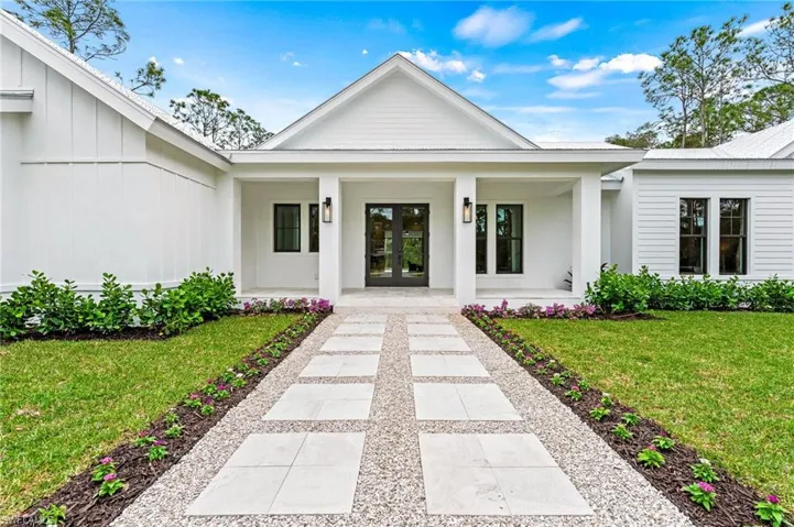 Doorway to property with custom french doors and a brushed marble walk and porch