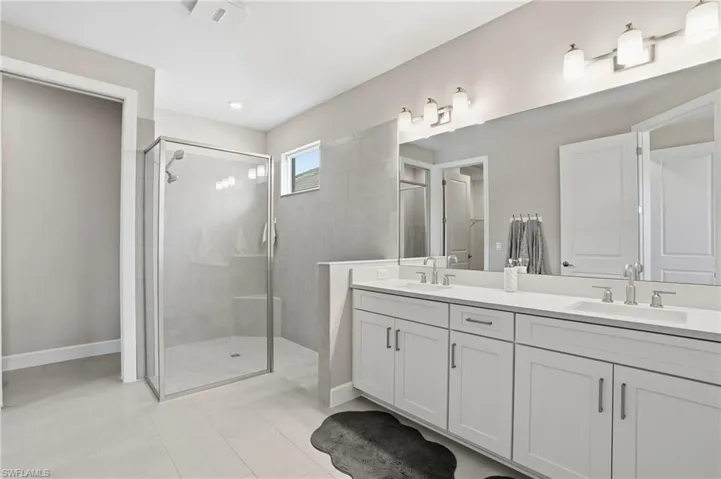 Bathroom featuring double vanity, a shower stall, and light tile patterned floors