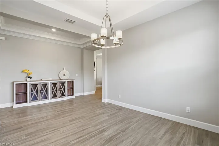 Unfurnished room featuring wood finish floors, a chandelier, and a tray ceiling