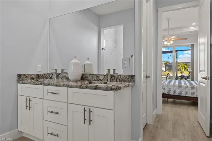 Bathroom featuring ceiling fan, vanity, ornamental molding, and woodplank tile flooring