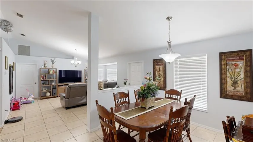 Tiled dining space with a chandelier and vaulted ceiling