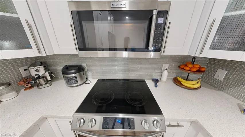 Kitchen with white cabinetry, backsplash, and stainless steel appliances