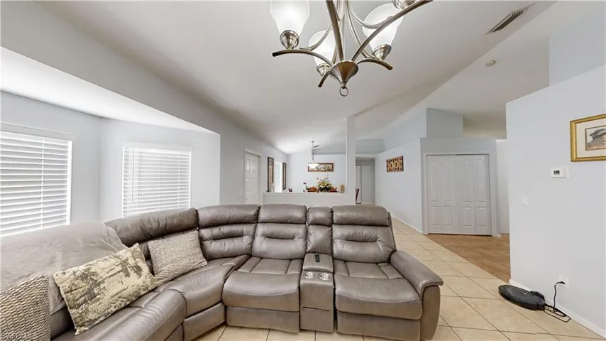 Tiled living room with vaulted ceiling and an inviting chandelier