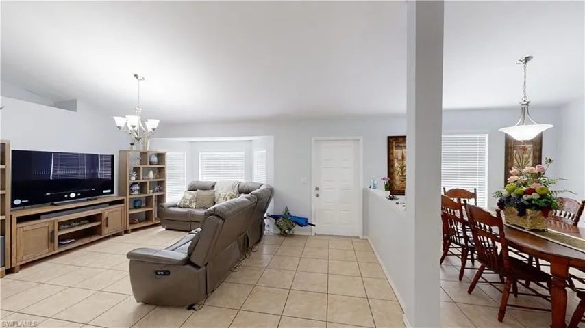 Tiled living room featuring lofted ceiling and a notable chandelier