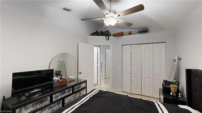 Bedroom featuring lofted ceiling, a closet, ceiling fan, and light tile patterned flooring
