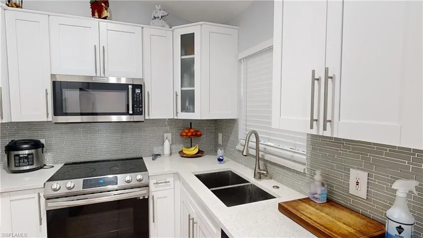 Kitchen featuring white cabinets, appliances with stainless steel finishes, sink, and light stone countertops
