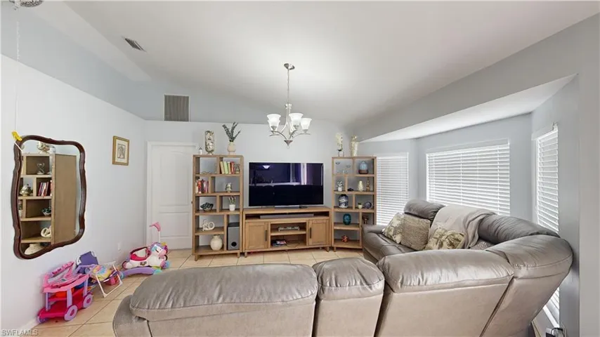 Living room featuring lofted ceiling, an inviting chandelier, and light tile patterned floors