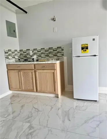 Efficiency kitchenette with white refrigerator and decorative backsplash