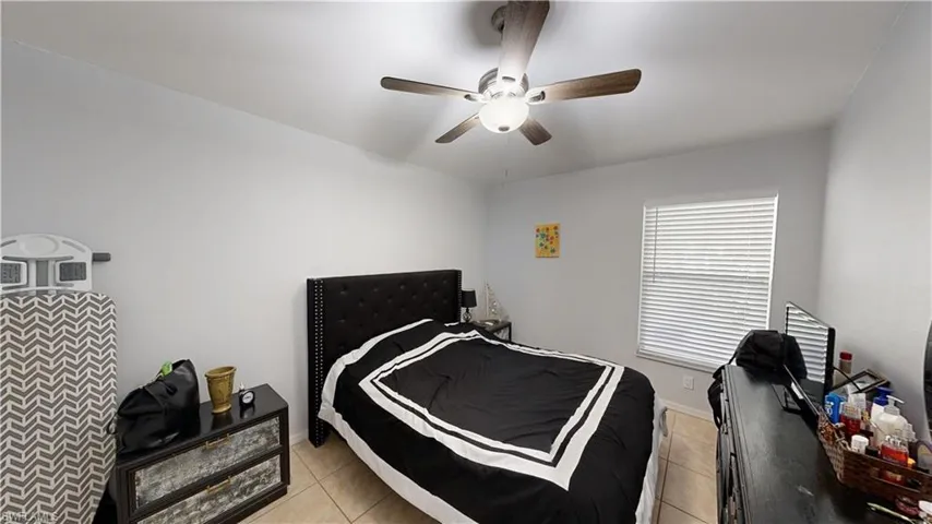 Bedroom with ceiling fan and light tile patterned floors